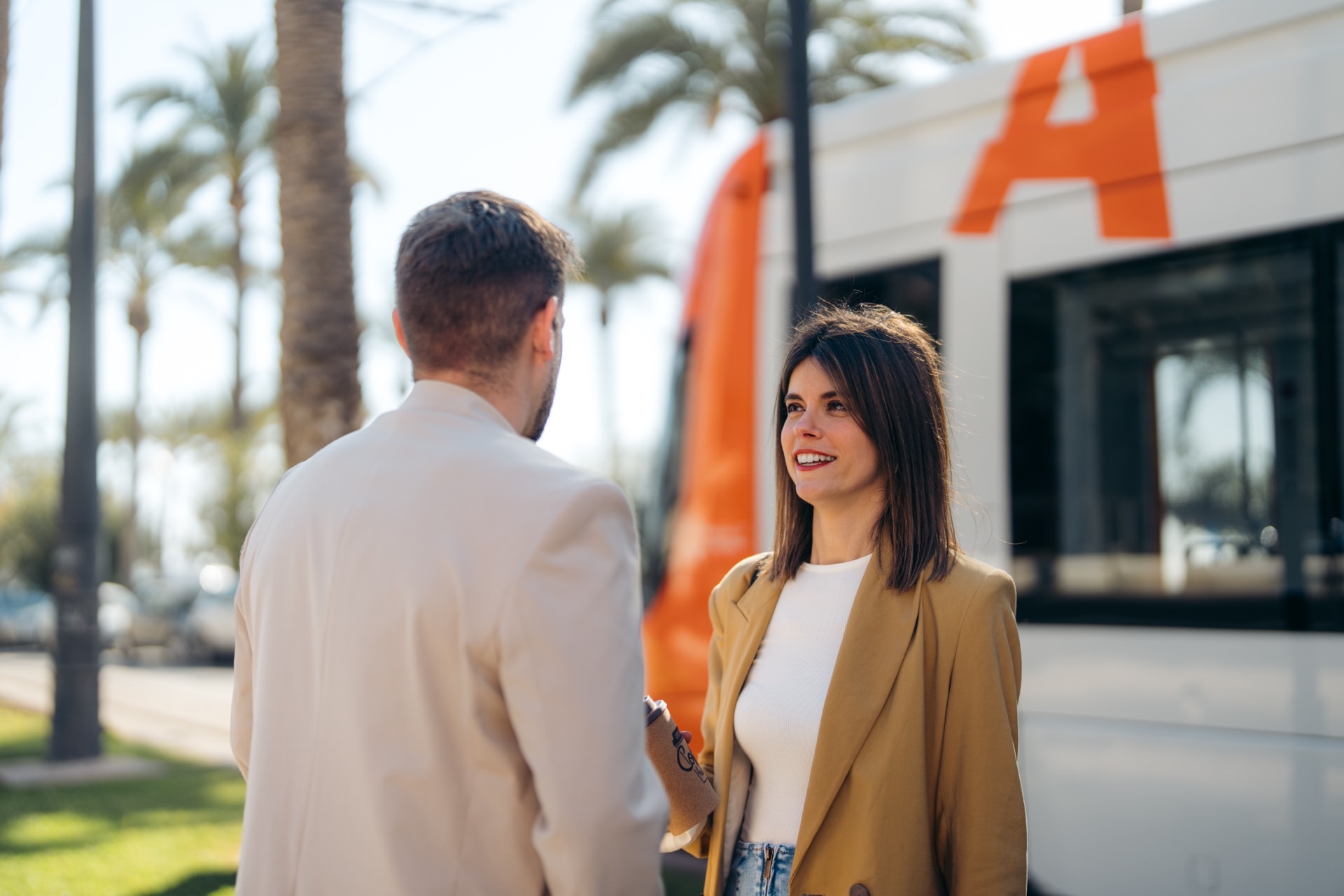 Smiling confident woman meeting male client communicating while waiting for public transport