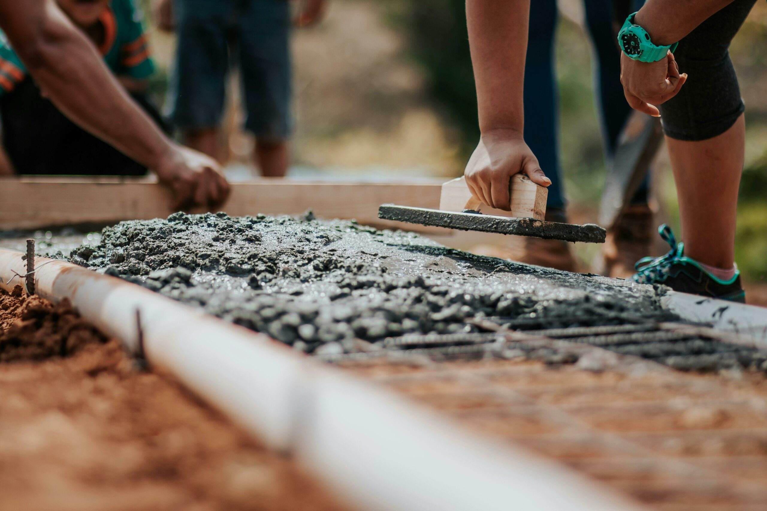 closeup shot of concrete workers smoothing wet concrete