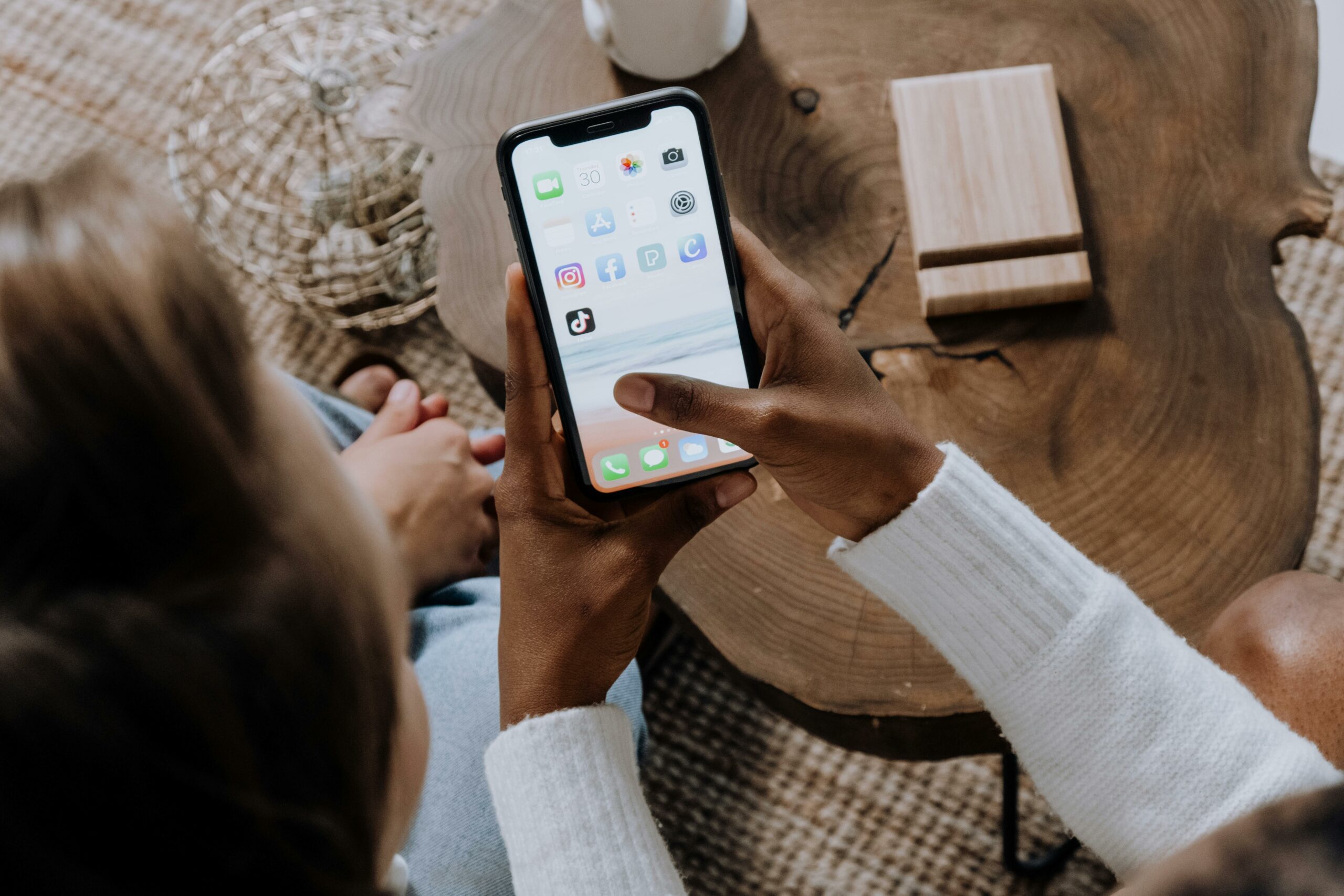 closeup of hands holding an iphone about to open the tiktok app