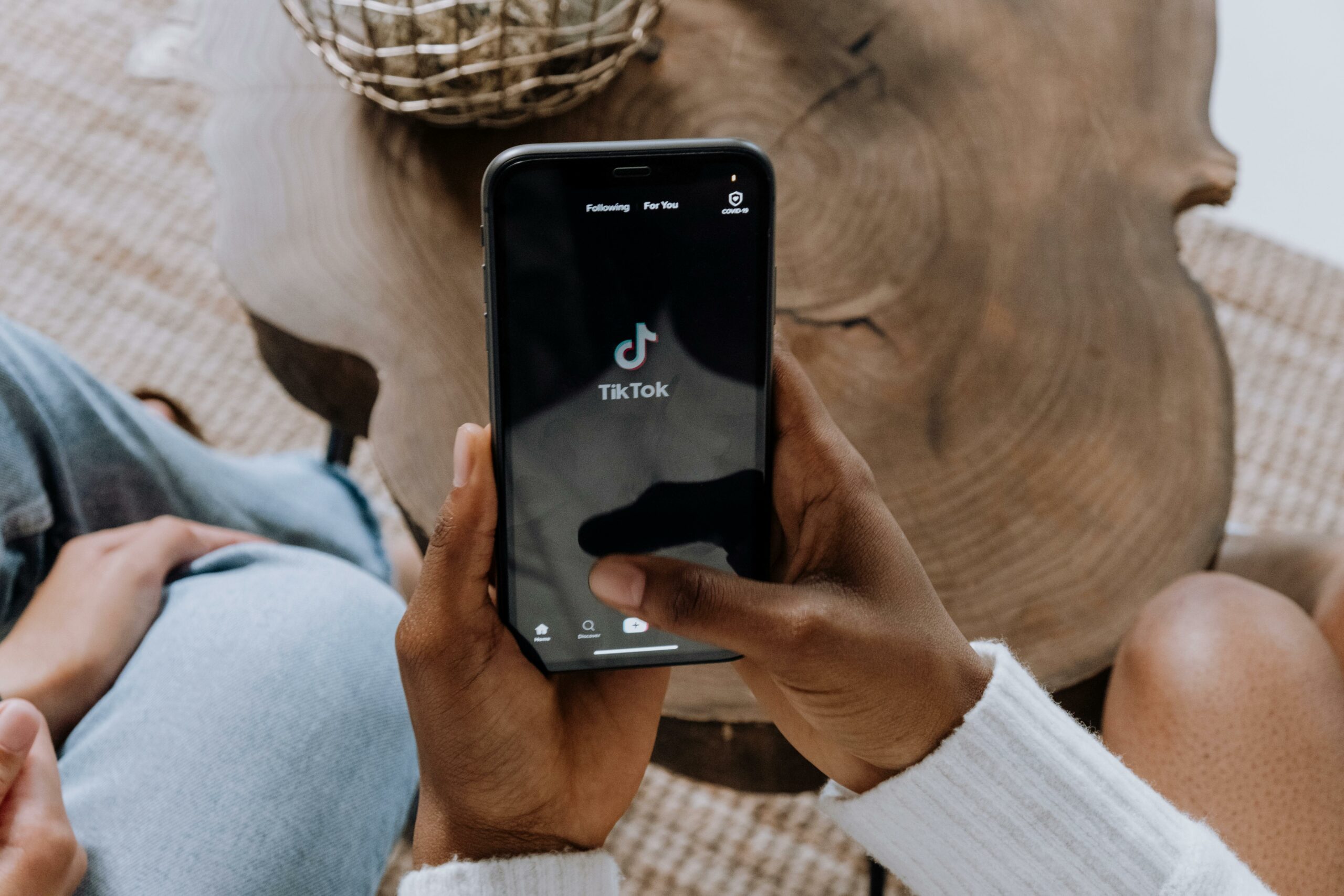 closeup of hands holding an iphone, navigating the tiktok app